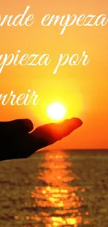 Hand holding the sun during a vibrant sunset over the ocean with a motivational quote.