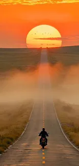 Motorcycle on road at sunset with a vast orange sky.