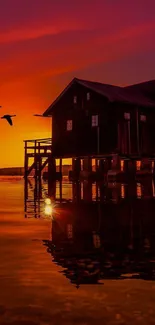 Lakeside house at sunset with vivid reflections and flying birds.