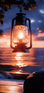 Lantern illuminating at sunset by the ocean waves.