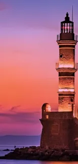 Lighthouse at sunset with orange and purple sky.