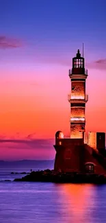 A serene lighthouse silhouette at vibrant sunset over calm ocean waters.