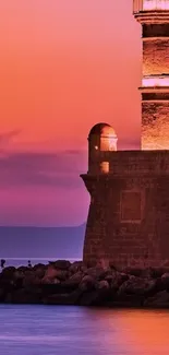 Lighthouse silhouette against a vibrant pink sunset on a tranquil ocean background.