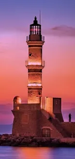 Lighthouse at sunset with pink and purple sky, serene seascape.