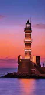 Lighthouse silhouetted against a vibrant sunset sky over the ocean.