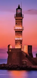 Lighthouse at sunset with vibrant sky hues reflecting over the ocean.