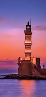 Lighthouse at sunset with vibrant colors in the sky and ocean waves.