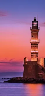 Lighthouse at sunset with orange and purple sky over calm ocean.