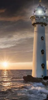 Lighthouse at sunset by the ocean with a serene sky and sun setting on the horizon.