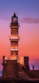 Lighthouse silhouette against sunset sky with orange and purple hues.