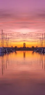 Purple and orange sunset over marina with boats reflected in calm waters.