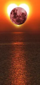 Sunset and moon over ocean with orange reflection.