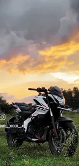 Motorcycle parked on grass at sunset with vibrant orange sky.