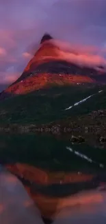 Mountain reflecting in calm water at sunset with purple sky.