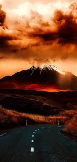 Winding road leading to a mountain under an orange sunset sky.