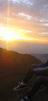 Person views stunning mountain sunset, surrounded by nature's colors.