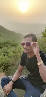 Man enjoys sunset view over mountains and forest, exuding tranquility.