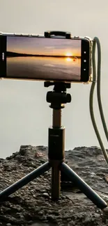 Smartphone capturing a stunning sunset on a tripod by the lake.