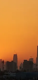 Orange sunset over city skyline with tall buildings.