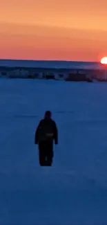 Silhouette on snowy field at sunset with colorful horizon.