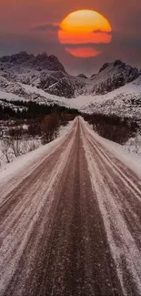 Breathtaking sunset over icy mountain road with snow-capped peaks.