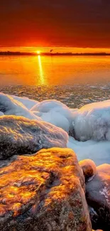 Orange sunset over icy rocks reflecting on a frozen lake.