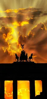 Silhouette of a monument against a vibrant orange sunset sky with dramatic clouds.