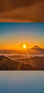 Sunset over mountain peaks with vibrant orange hue and clear sky.