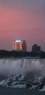 Niagara Falls at sunset with city skyline and pastel sky.