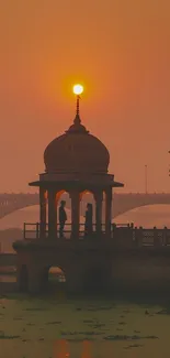Sunset behind a pavilion by the river with an orange sky.