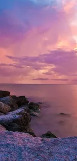 Purple sunset over rocky beach with vibrant sky.