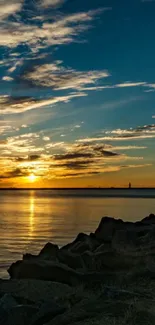 Serene lake sunset with rocks and vibrant sky.