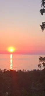 A beautiful sunset over a calm sea with pink and orange hues in the sky.