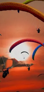 Paragliders with colorful canopies soar against a stunning orange sunset sky.