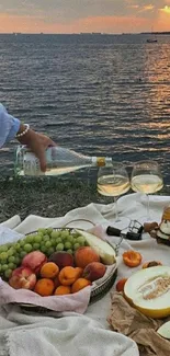 Picnic set by the sea during sunset with fruits and wine.