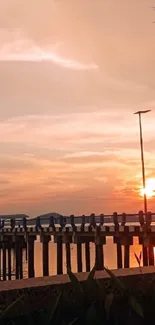 Serene sunset over a pier with warm colors and a tranquil ocean view.