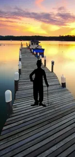 Silhouette on a pier with sunset hues reflecting on water.