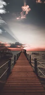 Dramatic sunset with pier and clouds over ocean.