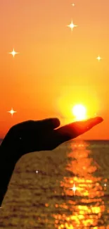 Hand holds the sun at sunset reflecting over the ocean with twinkling stars.