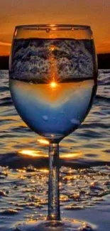 Wine glass reflecting sunset over ocean.