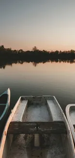 Tranquil sunset over lake with boats reflecting on calm water.