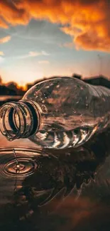 Plastic bottle on water reflecting a vibrant sunset sky.