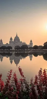 Sunset reflecting a palace over calm waters with garden in the foreground.