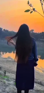 Woman by a serene river at sunset.