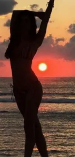 Silhouette of a woman against a vivid beach sunset.