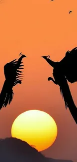 Silhouetted birds against orange sunset sky, creating a serene and elegant landscape.