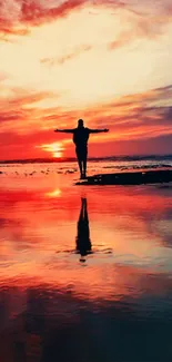 Person silhouetted against a vibrant sunset by the ocean with a stunning reflection.