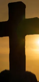 Silhouetted cross against a golden sunset sky, creating a peaceful mobile wallpaper.