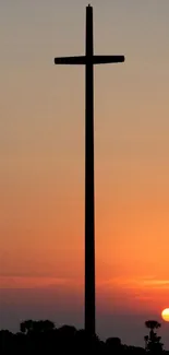 Silhouette of a cross against a vibrant sunset sky.