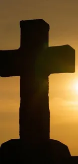 Silhouette of a cross against a vibrant orange sunset sky.